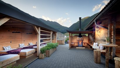 Holzterrasse mit Feuerstelle und Bergen im Hintergrund bei klarem Himmel