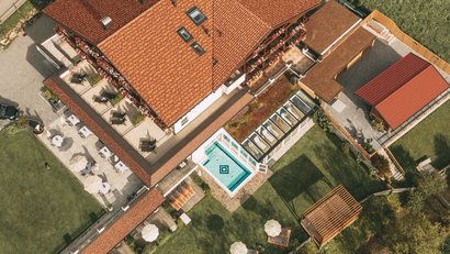 Luftaufnahme eines Hauses mit rotem Dach, Pool und umliegendem Garten