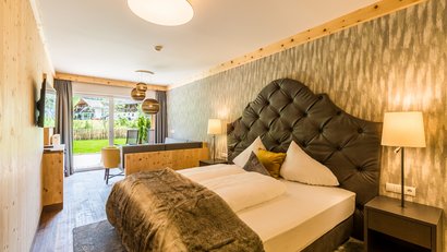 Modern eingerichtetes Schlafzimmer mit großer Bettdecke und Blick auf Terrasse