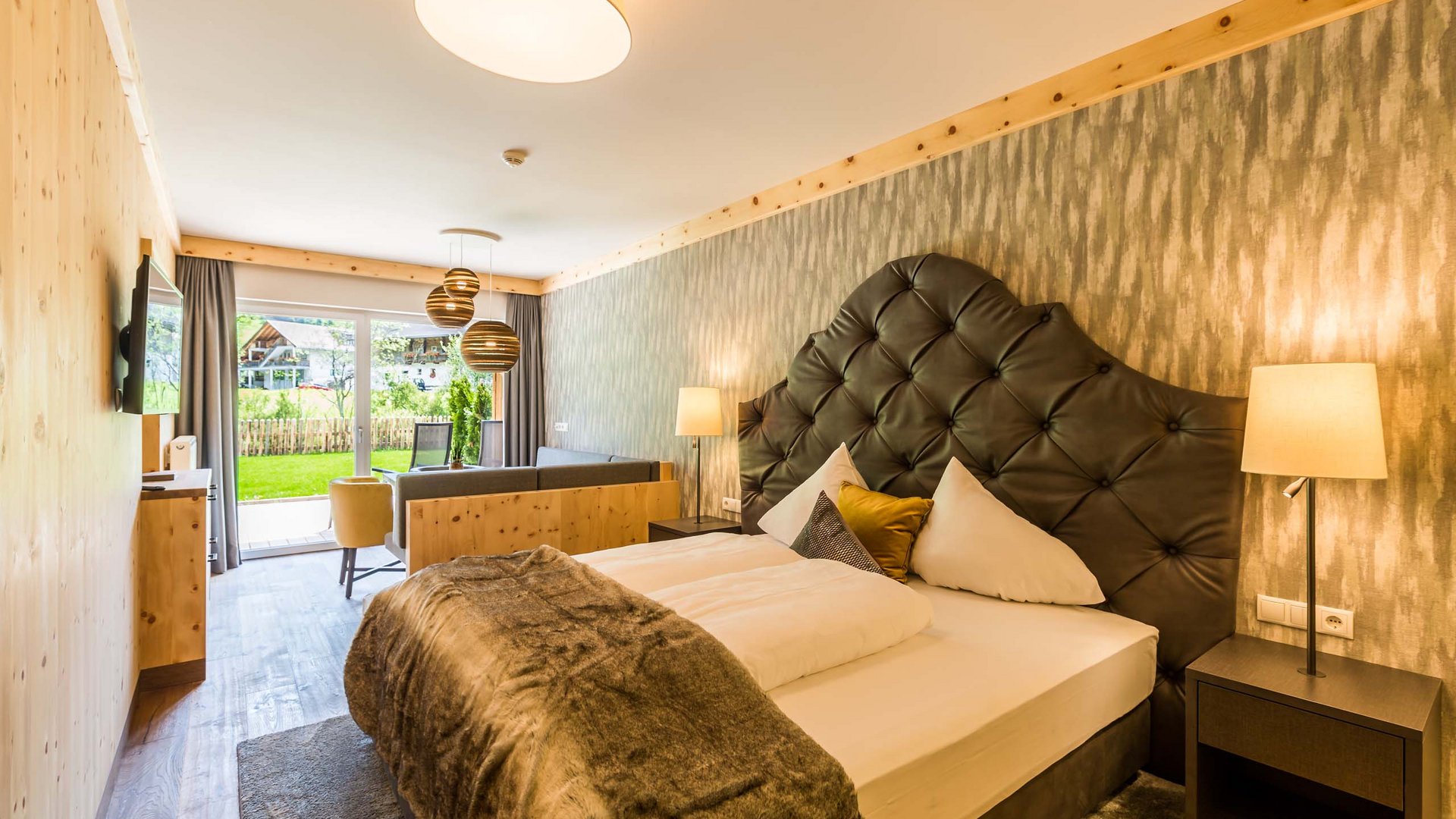 Modernes Hotelzimmer mit großem Bett und Terrasse mit Gartenblick