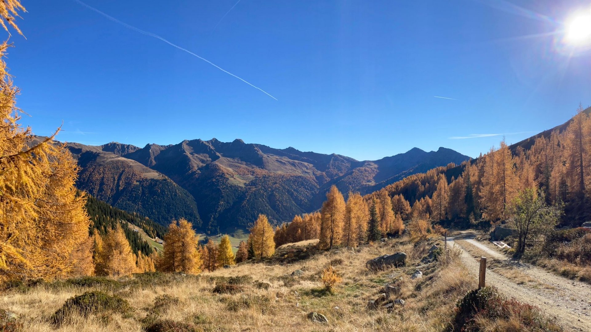 Herbstliche Berglandschaft mit Wanderweg und blauem Himmel