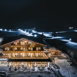 Beleuchtetes Chalet im Schnee bei Nacht mit winterlicher Landschaft