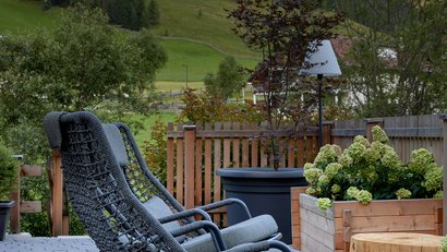 Zwei graue Schaukelstühle auf Terrasse mit Bergblick und Pflanzen