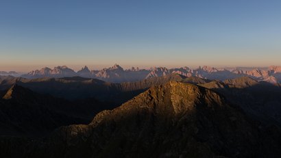 Bergpanorama bei Sonnenaufgang mit Gipfeln und blauem Himmel